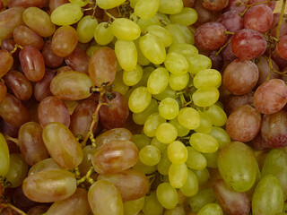 Large bunches of ripe pink and yellow  grape  lies on a table, background      