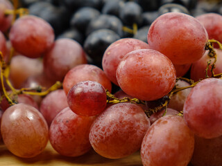 Large bunches of ripe black and pink grape lies on a table, background
