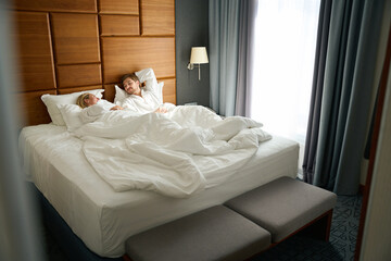 Fototapeta na wymiar Blonde with her boyfriend are talking in cozy hotel room