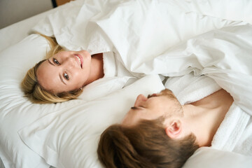 Obraz na płótnie Canvas Happy man and woman lying bed in hotel