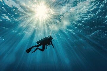 sun rays piercing through deep blue water with a diver as the subject - obrazy, fototapety, plakaty