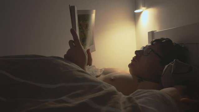Adult reading a book in bed with child at night