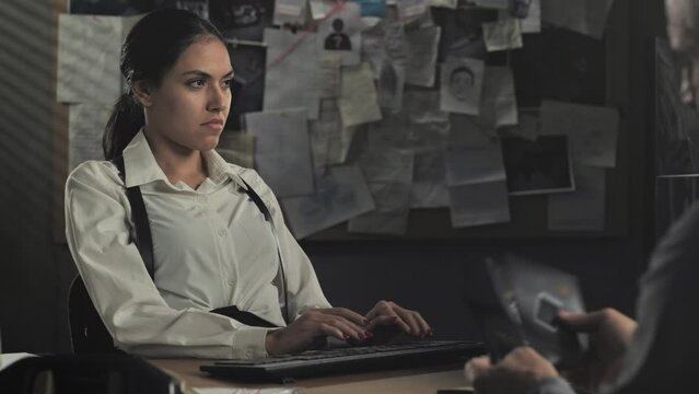 police detectives investigate on the murder case in office,policeman officer examing crime scene evidence while female cop is working at the computer
