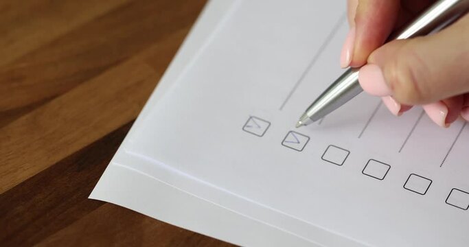 Person ticks boxes with pen completing to-do list. Checking grades and completing survey report concept