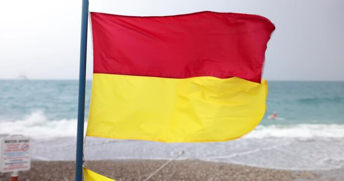 Closeup of red and yellow beach flag on beach. Lifeguard flags on seashore