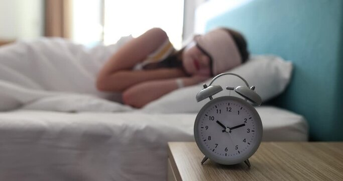 Alarm clock for 10 o'clock on table in children bedroom. Child sleeping soundly in mask in bedroom