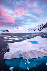 Floating iceberg with pool on the top of the iceberg with clear visible part under the water, glacier in the background and sunset sunrise sky