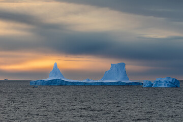 Iceberg swimming in the polar sea in front of midnight sun in Antarctica