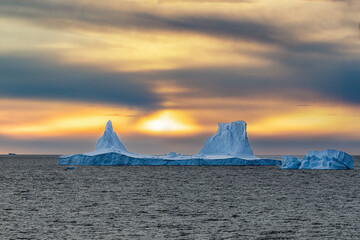 Iceberg swimming in the polar sea in front of midnight sun in Antarctica