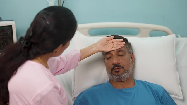 Shoulder shot, worried wife caring sick bedridden hospitalized husband at ward - concept of family bonding, emotional support and medical illness