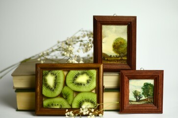sliced ​​kiwi in a wooden frame on a white background and books nearby
