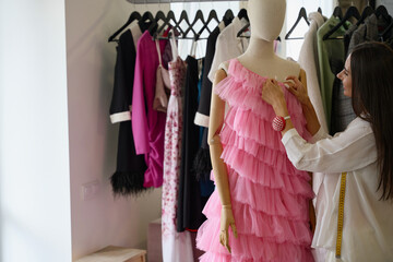 Smiling designer creates a pink evening dress