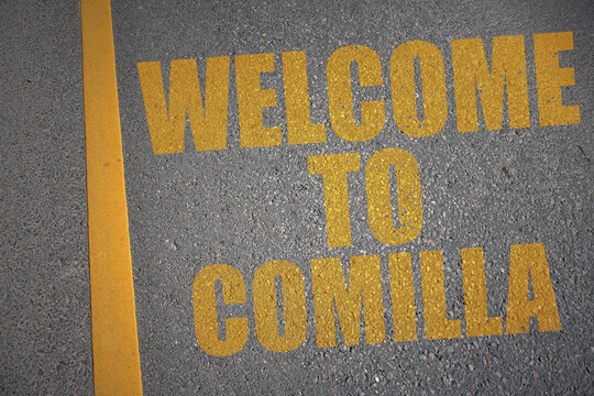 asphalt road with text welcome to Comilla near yellow line.