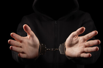 Unknown, indistinguishable thug or hucker in handcuffs and black clothes is arested.