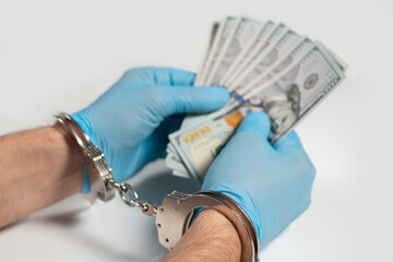 A doctor with dollar bank notes and handcuffs. concept of medical corruption, bribery, crime