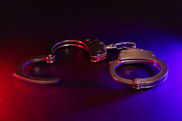 Silhouette of handcuffs. Image with the flashing red and blue police lights dark background.