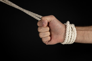Man's hand tied with a rope, vintage effect photo with noise. Pulling man out of a bad situation.