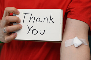 Dziękować za oddanie krwi, pacjent z napisem dziękuję i plasterkiem opatrunkiem na dłoni 