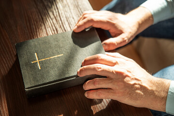 Obraz premium Hands of man holding Holy Bible at home. Lifestyle, natural aesthetic light.