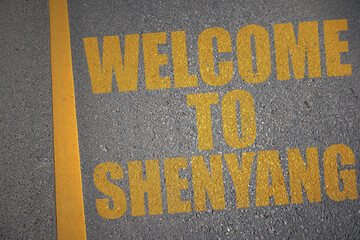 asphalt road with text welcome to Shenyang near yellow line.