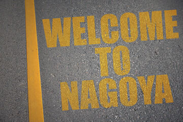 asphalt road with text welcome to Nagoya near yellow line.