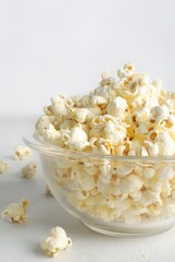 Popcorn in a glass bowl, isolated on white background.