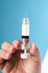 syringe for injection in the hands of a doctor on a blue background real context