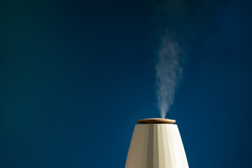 Aroma diffuser, humidify air, vaporize water, closeup of ultrasonic vapor, blue background