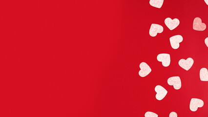 Top view of table decoration concept for Valentine's Day background. Paper cut hearts on a red background, space for text. Several objects on red wallpaper.