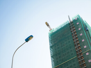 Street light post looking up high rise condo apartment under construction green safety nets netting...