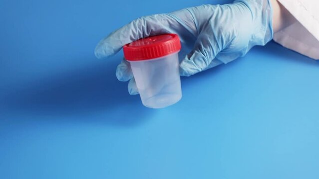 sperm donation, jar for male semen sample for fertilization and pregnancy, have children, in the hands of a doctor in a reproductive clinic on a blue background
