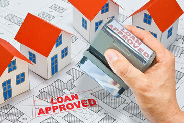 Loan approved concept with home model and stamp against an imaginary cadastral map