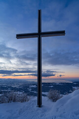 Panoramic view from a summit with summit cross onto Lake Constance during blue hour  in winter