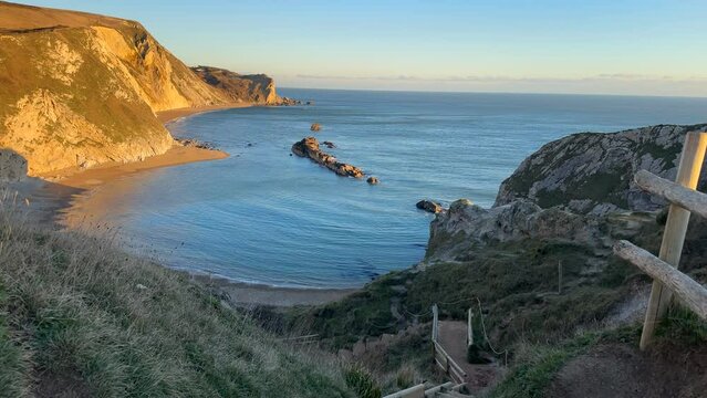 The sun goes down on the Jurassic coast and Durdle Door in Dorset with Seak Pink Trift growing on the top of the cliff in the foreground. Durdle Door, Dorset, Jurassic Coast, England, UK