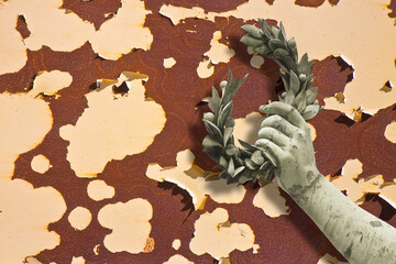 Hand holds a laurel wreath - concept image against a rusty metal background - Success and fame concept with copy space