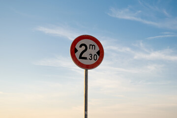 Width limit traffic sign, isolated sunset sky.
