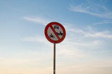 No entry for motorbike Cars or animal-drawn vehicles traffic sign, isolated sunset sky.