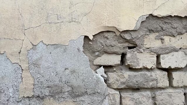 Background of a crumbling brick wall close-up. The texture of a crumbling wall