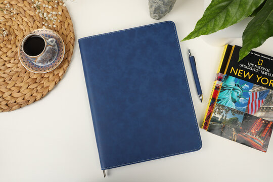 Leather pen and leather portfolio on desktop. with coffee and city guide image. nice desk top view. concept shot. Free space for mockup.. blue color.
