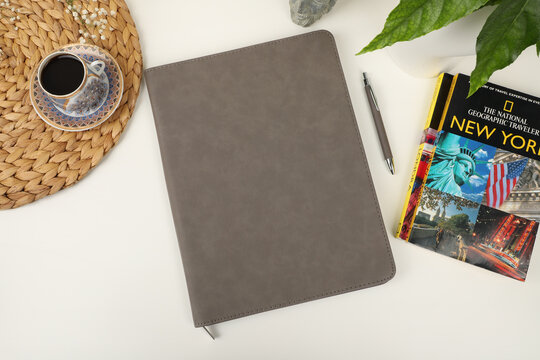 Leather pen and leather portfolio on desktop. with coffee and city guide image. nice desk top view. concept shot. Free space for mockup.. gray color.