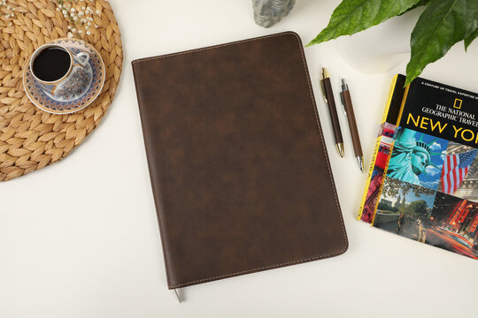 Leather pen and leather portfolio on desktop. with coffee and city guide image. nice desk top view. concept shot. Free space for mockup.. brown color.