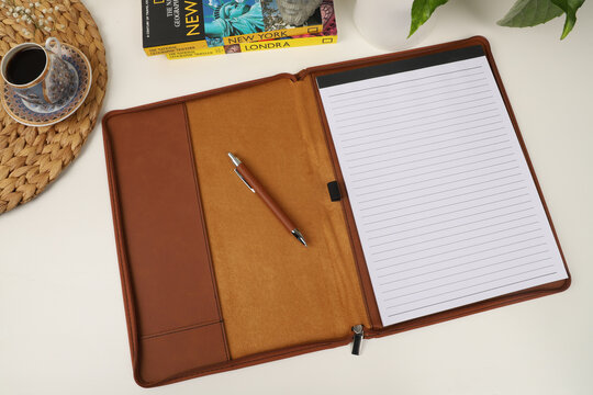 Leather pen and leather portfolio on desktop. with coffee and city guide image. nice desk top view. concept shot. Free space for mockup.