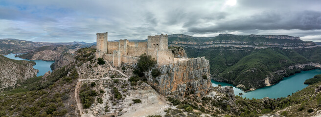 Aerial panoramic view of Chirel castle atop a rocky crag jutting out over el Jugar gorge in Cortes de Pallas, with triangular layout, arrow slits, parapets, moa, water tank, main tower