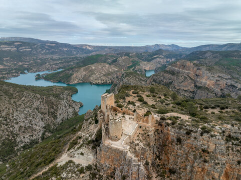 Aerial panoramic view of Chirel castle atop a rocky crag jutting out over el Jugar gorge in Cortes de Pallas, with triangular layout, arrow slits, parapets, moa, water tank, main tower