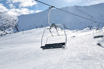 Cable car construction, Empty three seater chair against the backdrop of snowy mountain slope, ski...