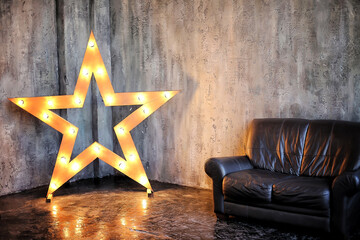 Decorative lighting star-shaped sign stylish decor. Vintage aesthetic  interior with retro style dark leather sofa