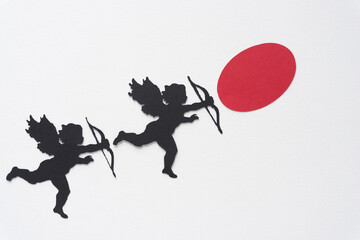 two Valentine's Day cupid silhouettes and red oval dot on blank paper