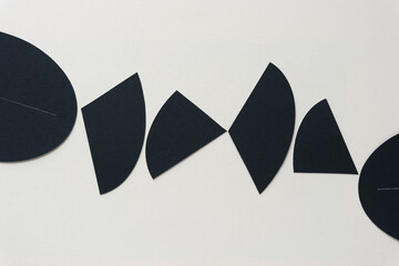 set of black paper shapes (mostly triangles with rounded edge) on blank paper background