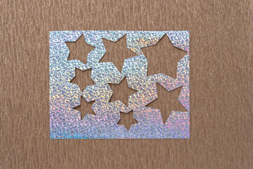 silver glitter crafting stencil sheet with various star cutouts on metallic crepe paper