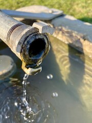 Wasser fliesst aus stahlleitung in den Brunnen